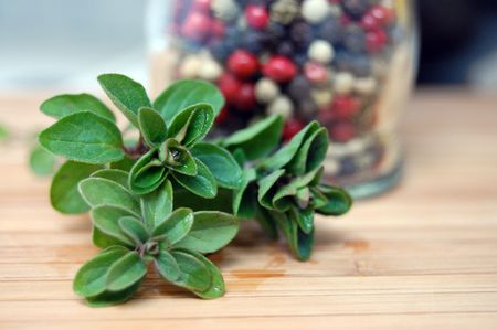 Fresh oregano and a bottle of mixed pepper on the wooden kitchen deskの写真素材