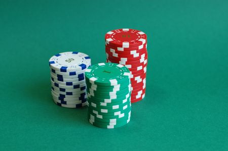 Three piles of casino tokens on a green backgroundの写真素材