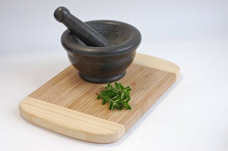 Gray mortar and freshly picked oregano on a wooden cutting desk on a white backgroundの写真素材