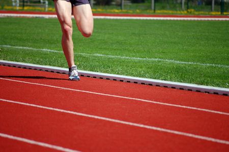 Athlete in shorts and running shoes warming up on the running track