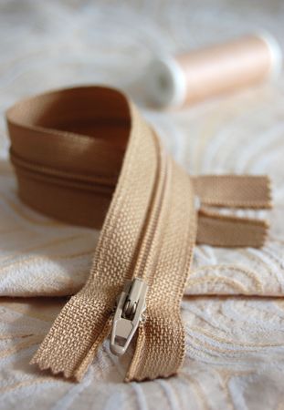 Brown zipper and thread on an embroidered cloth