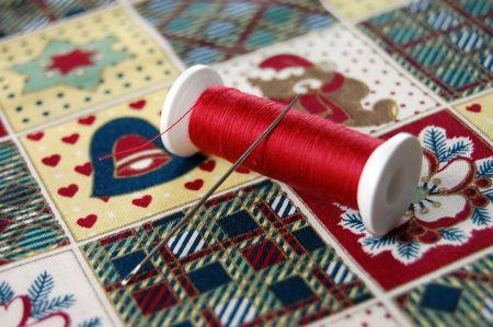 Needle and red thread on a fabric with Christmas pattern