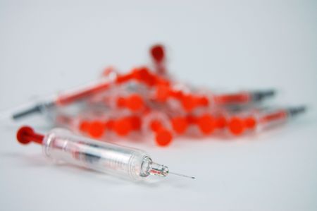 Injection ready for use with a pile of used injections in the backgroundの写真素材