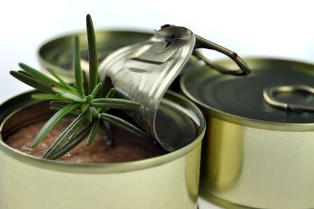 Open tuna can with fresh rosemary and two closed cans on a white backgroundの写真素材