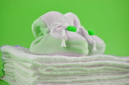 Green baby sleepers on a pile of cotton diapersの写真素材