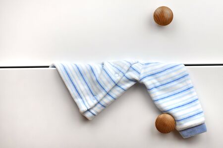 Baby sweater hanging from the white chest of drawersの写真素材