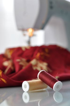 Red and yellow thread with a sewing machine in the background