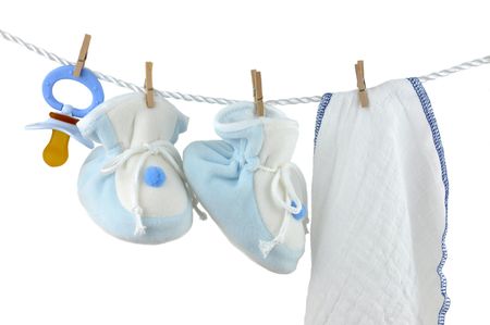 Blue pacifier, booties, and diaper hanging on a cord, isolated on whiteの写真素材