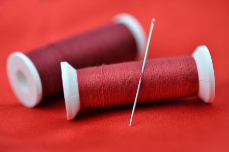 Needle and spools on red clothの写真素材