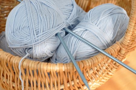 Blue wool and knitting needles in a wicker basket の写真素材