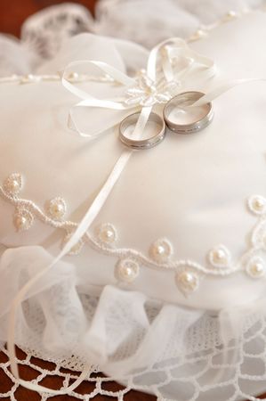 Two wedding rings on a heart shaped pillowの写真素材