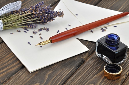 Fountain pen on empty letter with a bouquet of dried lavender on a wooden tableの写真素材