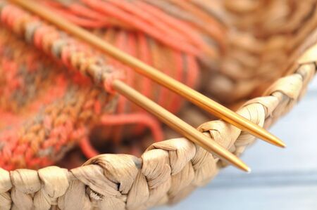 Knitting needles and yarn in autumn colors in a wicker basket