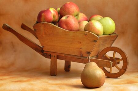 Small wooden wheelbarrow full of apples and a pearの写真素材