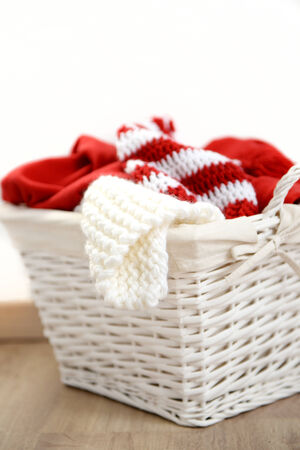 Red and white Christmas clothes in a wicker basket, isolated on whiteの写真素材