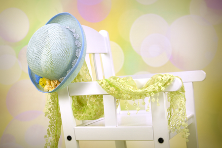 Blue hat hanging on white wooden chair with green scarfの写真素材