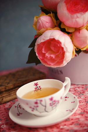 A cup of tea and buds of peonies on a tableの写真素材