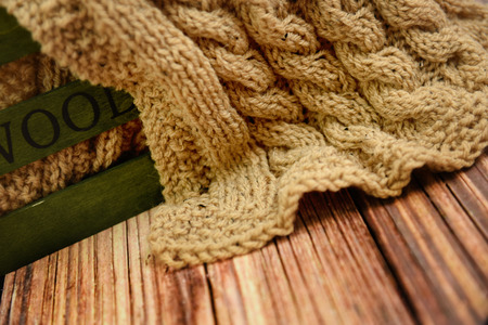 Part of hand knitted cloth lying in a wooden box on a tableの写真素材