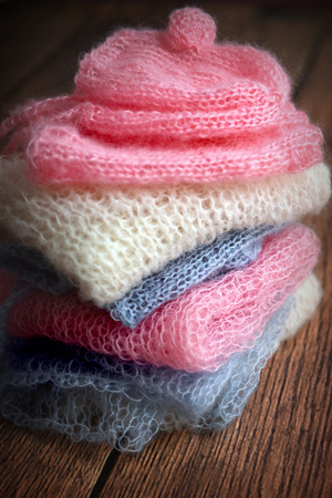 Pile of soft mohair hand knit clothes in pink, blue and whiteの写真素材