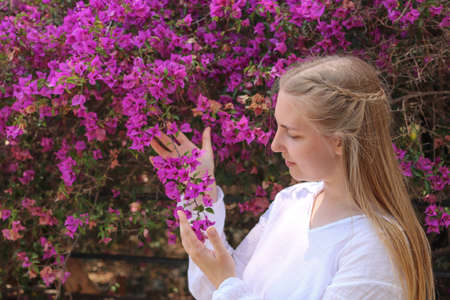 Blonde girl posing and smelling bougainvillea
