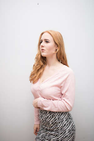Beautiful long red health hair of young attractive woman isolated white background pink shirt zebra skirtの写真素材