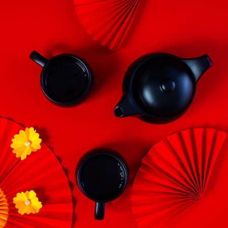 Chinese New year Classy red square composition with teapot, teacups and paper fans with yellow flowers.の写真素材