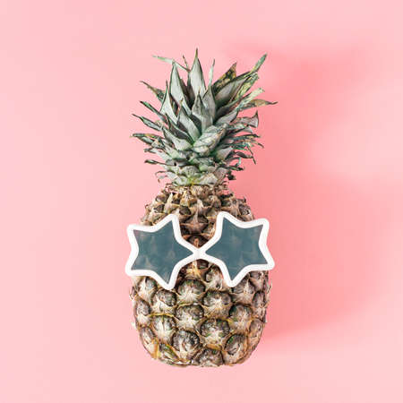 Pineapple with sunglasses lying on pastel pink background. Bright summer's day simple scene.の写真素材
