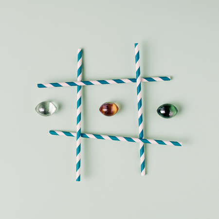 Tic Tac Toe with straws and gem stones on pastel light green background.の写真素材