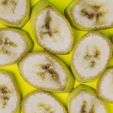 Banana slices pattern on lime green background. Simple square composition.の写真素材