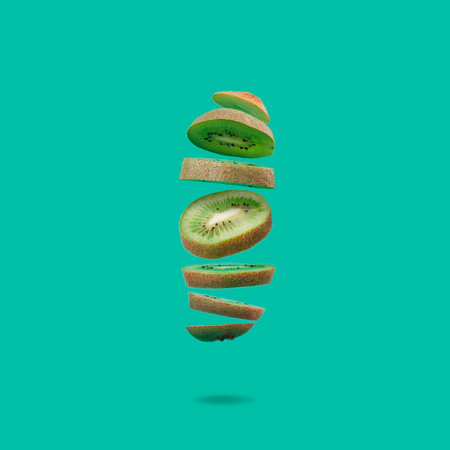 Flying fruit. Hovering kiwi slices on intense pastel turquoise background.の写真素材