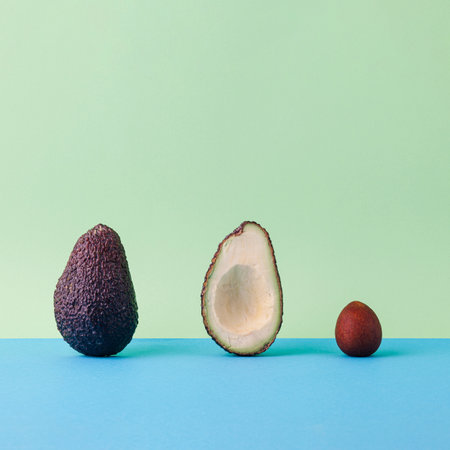 Stages of life. Avocado from outside, sliced and inside. Fruit seed, crust and cross section. Square composition on pastel green and blue.の写真素材