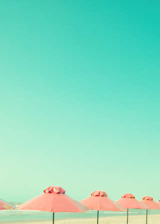 Vintage summer beach with pink umbrellasの写真素材