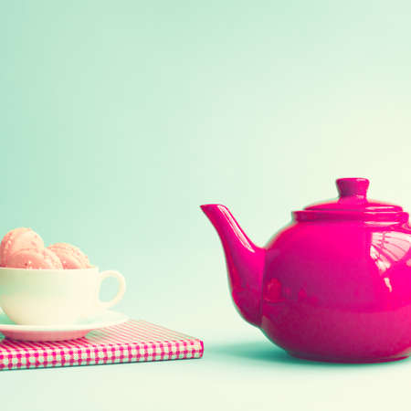 Macaroons in a coffee cup and red teapotの写真素材