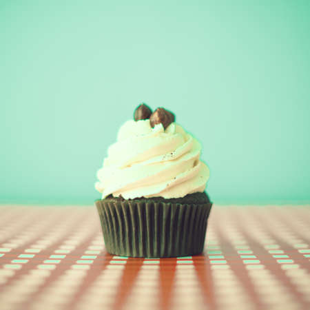 Hazelnut cupcake over turquoise and checkered backgroundの写真素材