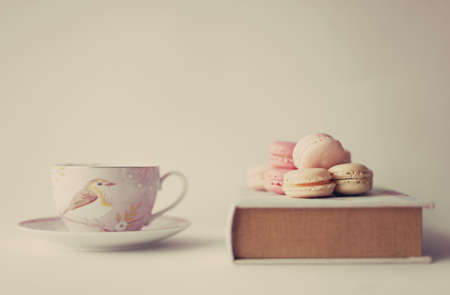 Macaroons over a vintage book and tea cupの写真素材
