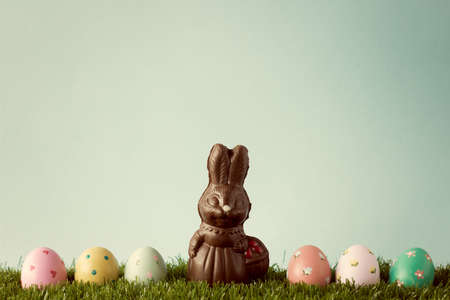 Vintage chocolate easter bunny with easter eggs over grassの写真素材