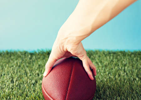 Vintage football over grass being heldの写真素材