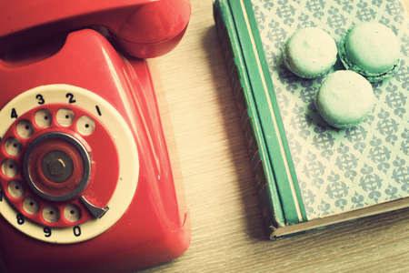 Vintage red telephone and macaroons over bookの写真素材