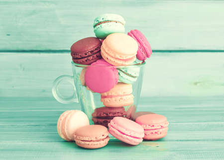 Colorful macaroons in a cup over turquoise wood