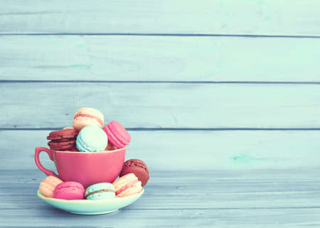 Colorful macaroons in a cup over turquoise woodの写真素材