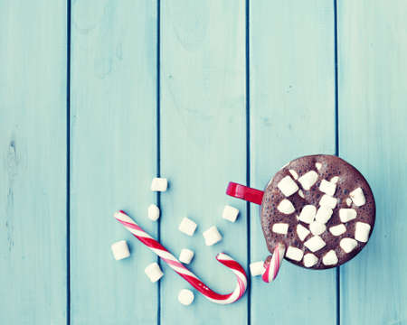 Chocolate cup with marshmallows and candy canes over woodの写真素材