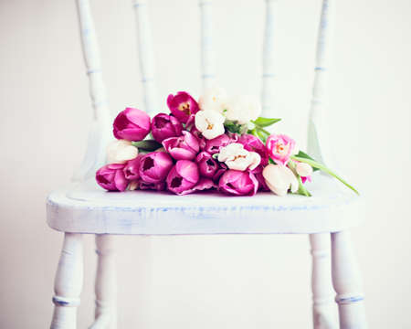 Pink and white tulips over a vintage white chairの写真素材