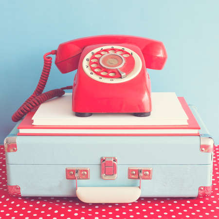 Vintage red telephone over books and briefcaseの写真素材