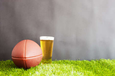 Vintage football and beer glass over grass and black backgroundの写真素材