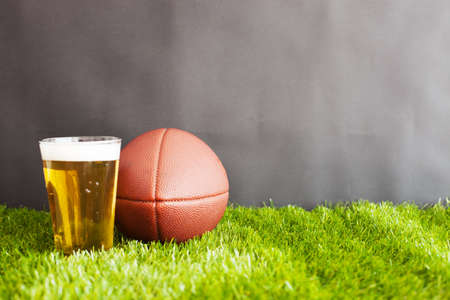 Vintage football and beer glass over grass and black backgroundの写真素材