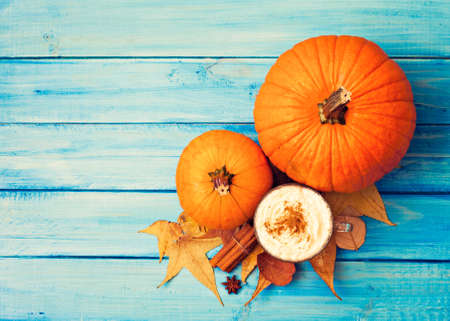Coffee cup, autumn leafs, and spices over turquoise woodの写真素材