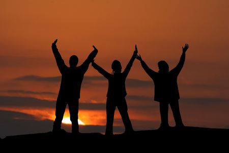 Three girls jumping up together at sunsetの写真素材