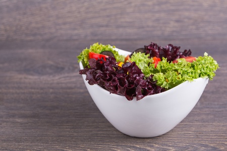 Fresh salad in white plate on wooden backgroundの写真素材
