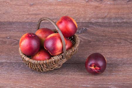 Fresh peaches in a basket on a wooden backgroundの写真素材