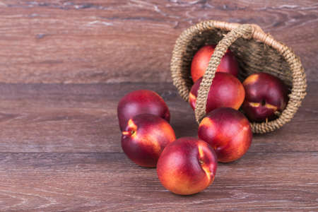 Fresh peaches in a basket on a wooden backgroundの写真素材